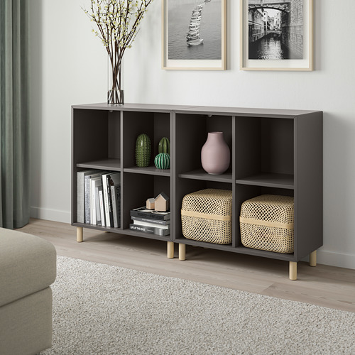 Una sala de estar moderna con un mueble de almacenamiento EKET negro, libros, decoración y un sofá beige.