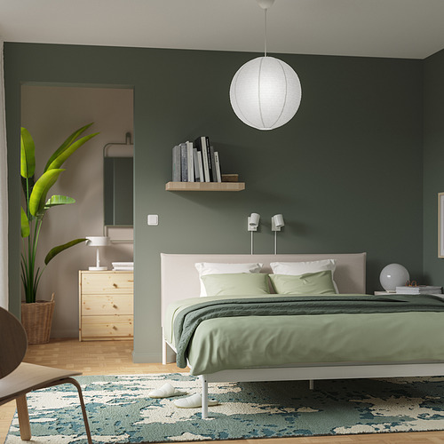 Dormitorio moderno con lámpara GULLSUDARE, paredes verdes, cama blanca.