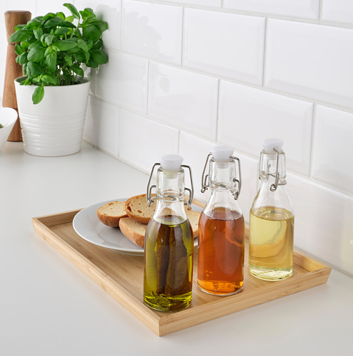 Tres botellas KORKEN en bandeja, con líquidos, junto al pan y la planta.