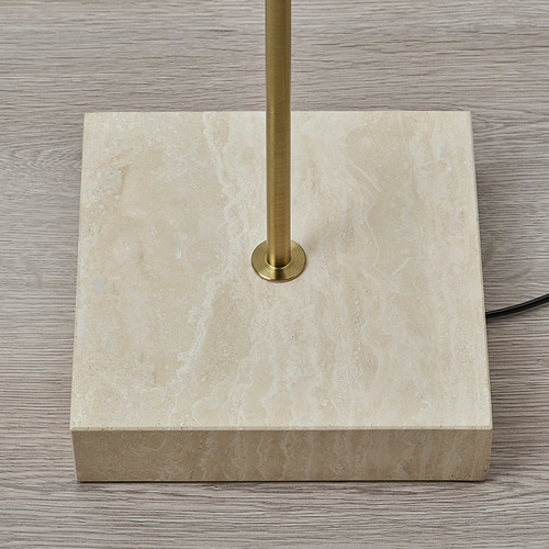 La base de una lámpara de alta calidad hecha de travertino natural con un soporte de color latón, que refleja la elegante artesanía.