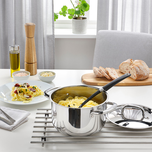 Una escena de cocina moderna con ollas y platos de acero inoxidable en una estufa.