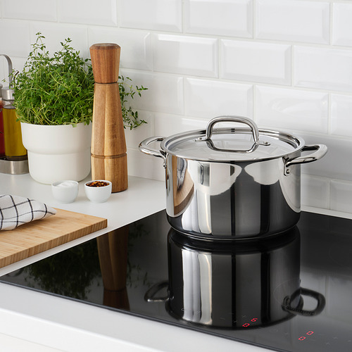 Cocina moderna con cocción de inducción, mortero, hierbas aromáticas y toalla.