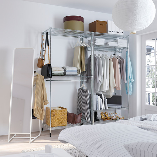 Dormitorio con estantería plateada, espejo, cama y lámpara.