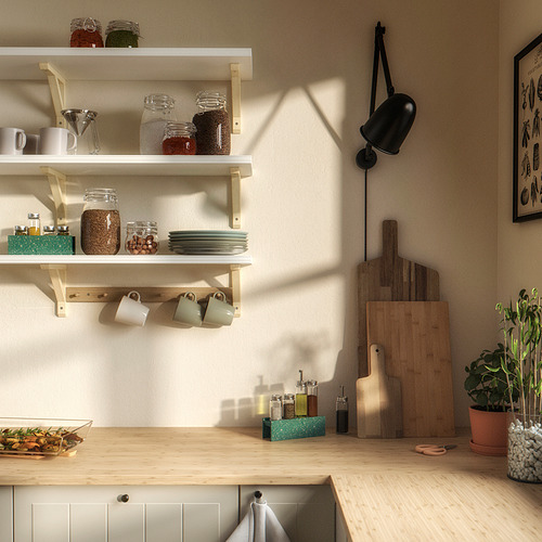 Encimera de cocina con encimera de madera, armario blanco, estantes con frascos, tazas, tablas de cortar y plantas verdes.