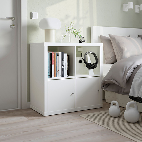 Unidad de almacenamiento de cubos KALLAX blanca con libros, auriculares y pesas rusas; Dormitorio pequeño y minimalista con suelos de color claro.