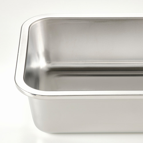 Recipiente de acero inoxidable para alimentos con bordes lisos y superficie brillante, que refleja la luz sobre un fondo blanco.