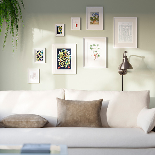 Sala de estar moderna con pared de galería colorida, pintura verde, sofá blanco y planta.