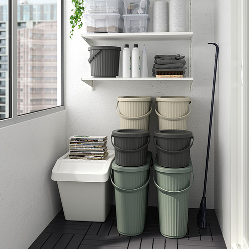 Varios contenedores DAMMÄNG verdes/grises apilados cerca de una ventana, ideales para residuos pequeños, con un contenedor blanco más pequeño encima.