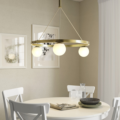 Lámpara colgante de latón con tres globos de cristal sobre la mesa de comedor, que emiten una luz cálida.