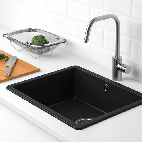 Fregadero de cocina moderno con grifo de acero inoxidable, material de cuarzo negro y colador con brócoli.