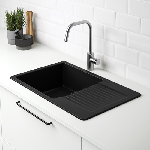 Fregadero de cuarzo negro con escurridor, grifo integrado, encimera blanca.
