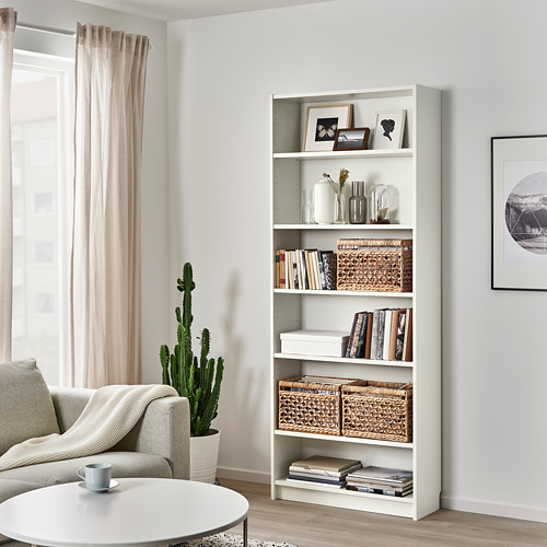 Sala de estar con cesta de ratán TÄTING en estantería billy, cerca del sofá, la mesa y el cactus.