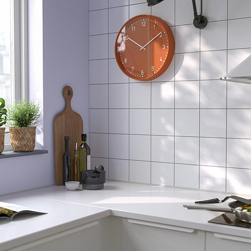 Reloj redondo de color naranja sobre la encimera de la cocina.