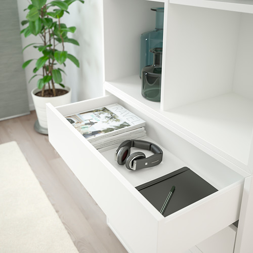 Cajón EKET blanco con revistas, auriculares y una computadora portátil, que muestra el almacenamiento organizado.