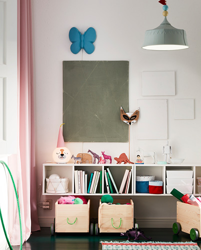 Habitación infantil con estanterías SMÅGÖRA. Estanterías de madera con juguetes y libros. Decoración de pared de mariposa azul, lámpara colgante verde, cortinas de colores.
