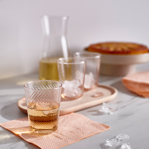 Vasos KLIPPLAX en la mesa con tarta. Liso por fuera, texturizado por dentro. Tazas pequeñas y transparentes cerca de un plato para servir más grande.