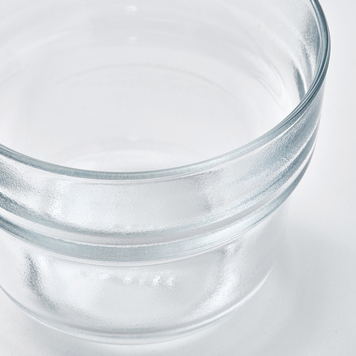Primer plano de una taza de vidrio transparente y texturizado. El vidrio aparece liso y pulido, mostrando reflejos de luz, enfatizando su calidad.