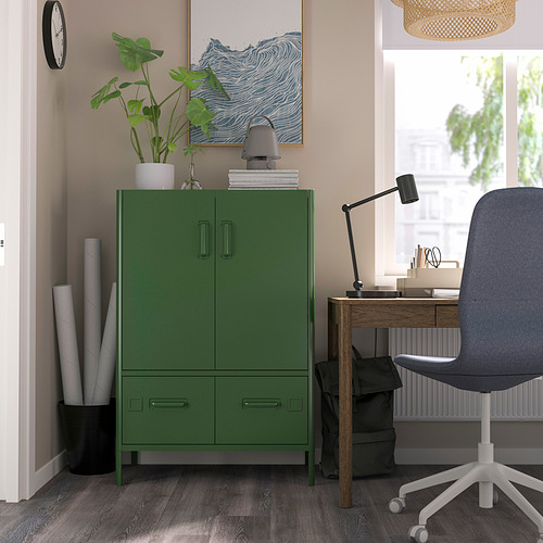 Despacho moderno con armario IDÅSEN verde, silla gris, escritorio de madera junto a la ventana, planta, lámpara y obras de arte.