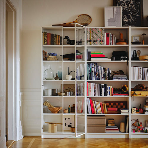 Estantería blanca BILLY con varios libros y artículos de decoración en estantes.