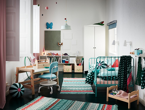 Luminosa habitación infantil con estantería turquesa SMÅGÖRA, escritorio de madera, silla azul y alfombra de colores.