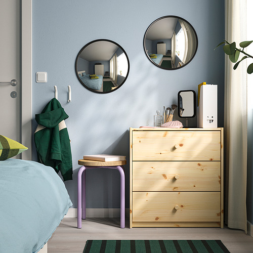 Dos espejos convexos con marco negro en la pared azul sobre una cómoda de madera clara con ropa de cama azul y toalla verde.