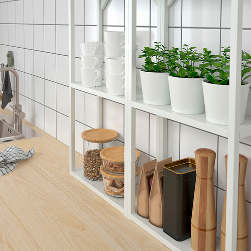 Estante de cocina con plantas en macetas y frascos; hierbas en macetas blancas, tazas apiladas.