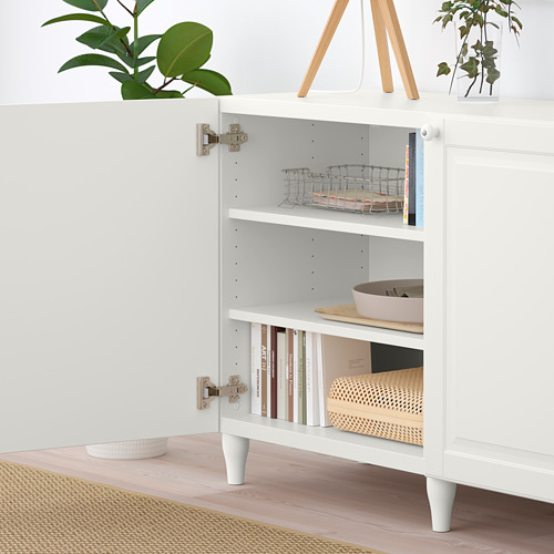 Armario blanco BESTÅ con estantes ajustables, almacenamiento de libros y cajas. Las plantas decoran la parte superior.