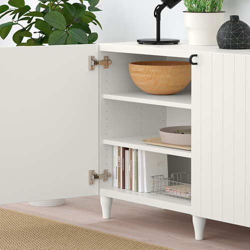 Mueble de almacenaje BESTÅ blanco con estantes ajustables. El estante superior exhibe un cuenco de madera. El estante inferior contiene libros, bandeja y canasta.