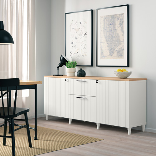 Aparador blanco BESTÅ con tapa de madera, 2 puertas, 2 cajones, estantes. Obra de arte arriba, cuenco de cítricos, planta, lámpara.