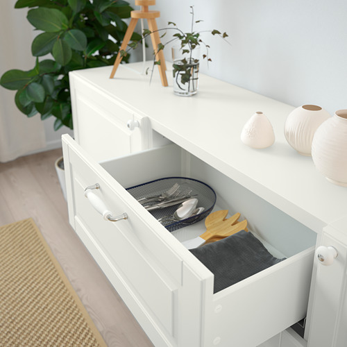 Cajón blanco abierto que revela artículos de cocina organizados, incluida una tabla de cortar y utensilios. Mecanismo de cierre suave implícito.