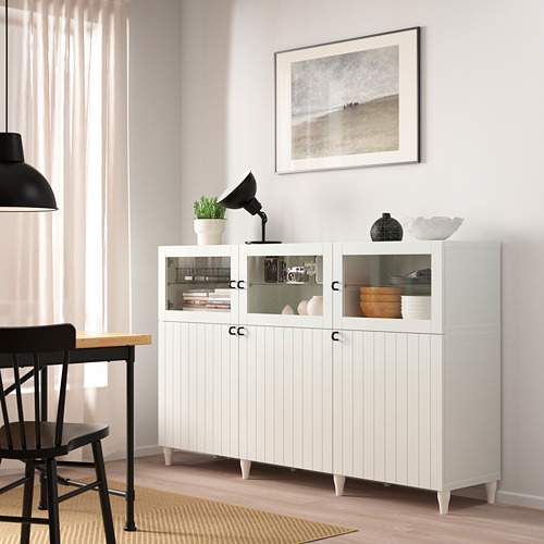 Aparador con puerta de cristal BESTÅ en el comedor con arte costero, cuencos, plantas.
