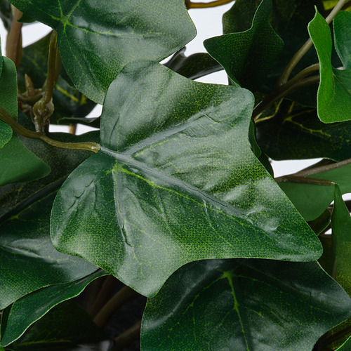 Primer plano de hojas de plantas artificiales realistas, elaboradas con plástico reciclado, que muestran una textura verde vívida y vetas realistas.