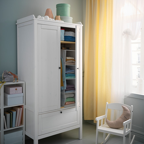 Armario infantil con ropa doblada, juguete, sillas, cortina amarilla, pared azul