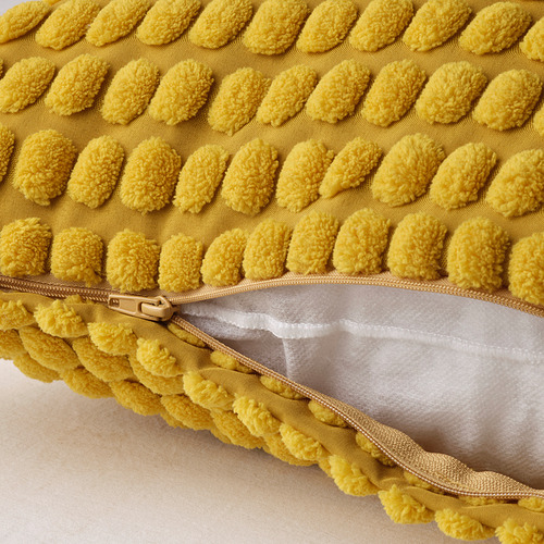 Funda de cojín amarilla con hileras de protuberancias suaves y texturizadas y abertura con cremallera, confeccionada en poliéster reciclado.
