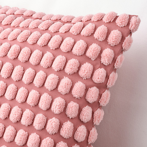 Funda de cojín rosa claro con un intrincado patrón texturizado, confeccionada con material suave y reciclado. Cierre de cremallera para facilitar el lavado.