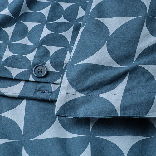 Primer plano de una funda nórdica estampada en azul oscuro con cierre de botón. Los círculos y triángulos forman un diseño moderno de mediados de siglo que se repite.