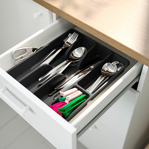 Cajón de cocina abierto que muestra una bandeja de cubiertos organizada con secciones para tenedores, cucharas, cuchillos y bolígrafos de colores.