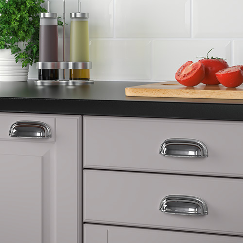 Gabinetes de cocina modernos con manijas de tazas cromadas y tomates en rodajas en el mostrador.