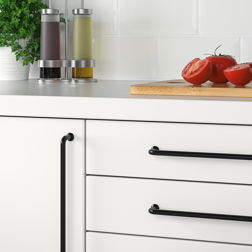 Armarios de cocina blancos con tiradores BAGGANÄS negros; Corta los tomates en la encimera.