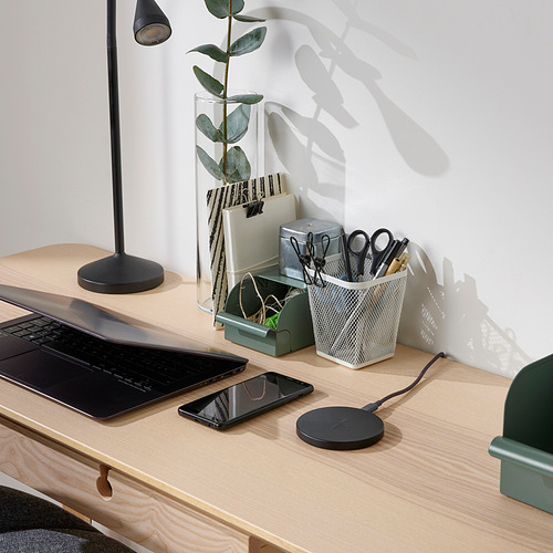 Escritorio de madera con lámpara de luz, planta verde, ordenador portátil, teléfono, cargador inalámbrico LIVBOJ negro, papelero de malla gris.