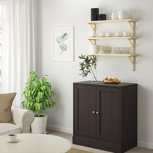 Sala de estar moderna con estante TREHULT, platos blancos, frutas, plantas, arte.