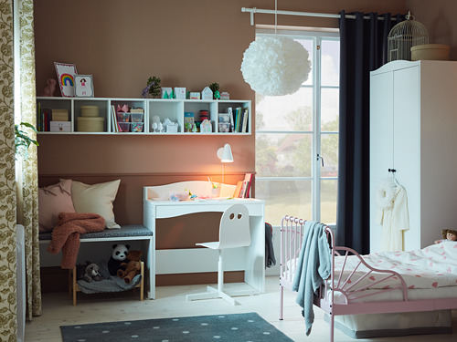 Habitación para niños con escritorio blanco, cama y estante SMÅGÖRA. Espacio luminoso y organizado con juguetes, libros y luz natural.