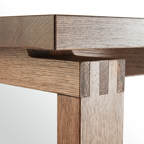 Detalle de esquina de mesa de madera, con vetas de roble y acabado claro.