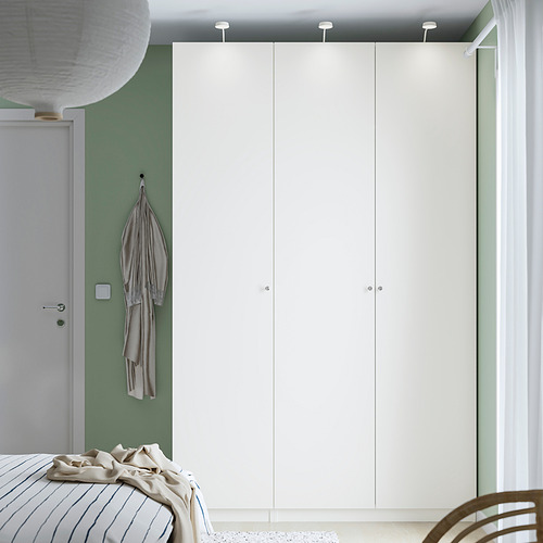 Habitación moderna con armario PAX, ropa de cama beige y prenda colgada. Estilo minimalista con paredes verdes.