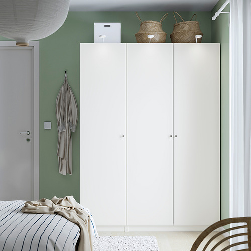 Armario blanco ikea PAX al lado de la puerta, tres secciones, cestas tejidas, toalla de rayas, cama con edredón de rayas.