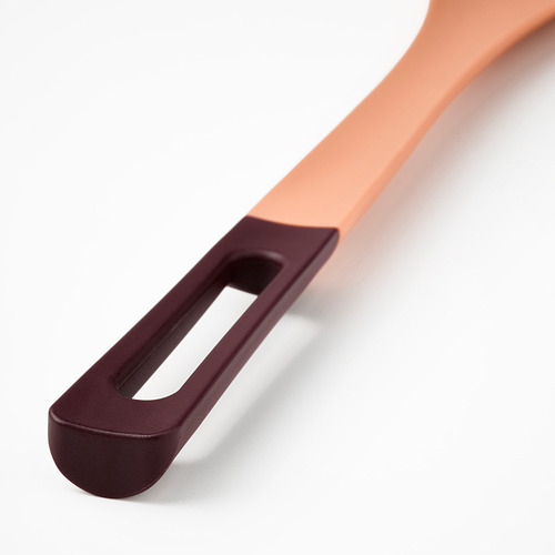 Primer plano de una cuchara de cocina moderna y colorida con mango ergonómico y punta de silicona.