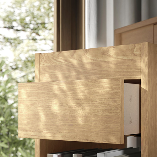 Cajonera de madera con dos cajones vistos, uno de ellos parcialmente abierto, en acabado madera natural claro. Construido con un diseño simple y limpio.