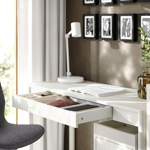 Un escritorio blanco con un cajón abierto que muestra el contenido.