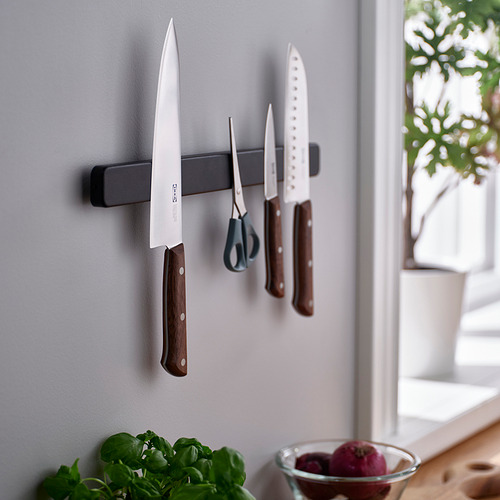 Un moderno soporte de pared para cocina sostiene cuchillos y tijeras; Práctico para la preparación cerca de una ventana con hierbas y frutas frescas debajo.