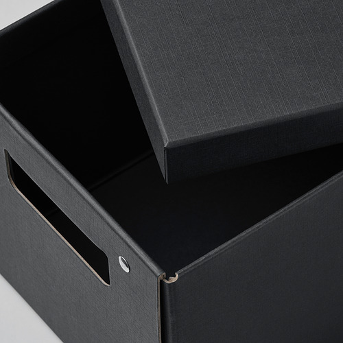 Caja de almacenamiento negra con tapa parcialmente abierta, asas y bordes artesanales que muestran un diseño de alta calidad.